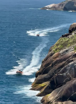 Lancha navegando junto ao costão